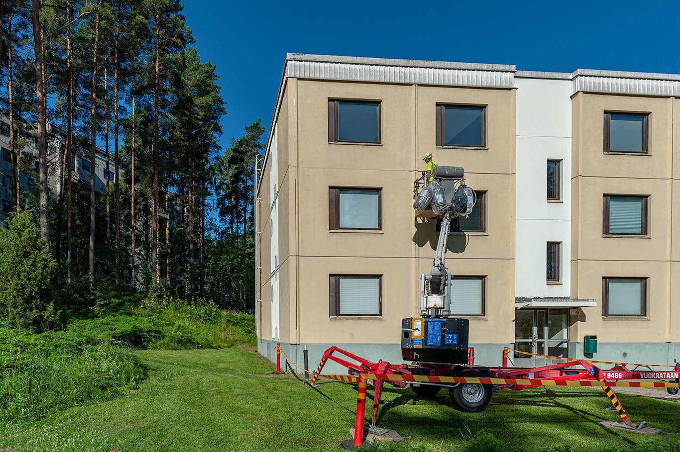 Kerrostalon julkisivun saumauksessa käytettävä nostin työmaalla