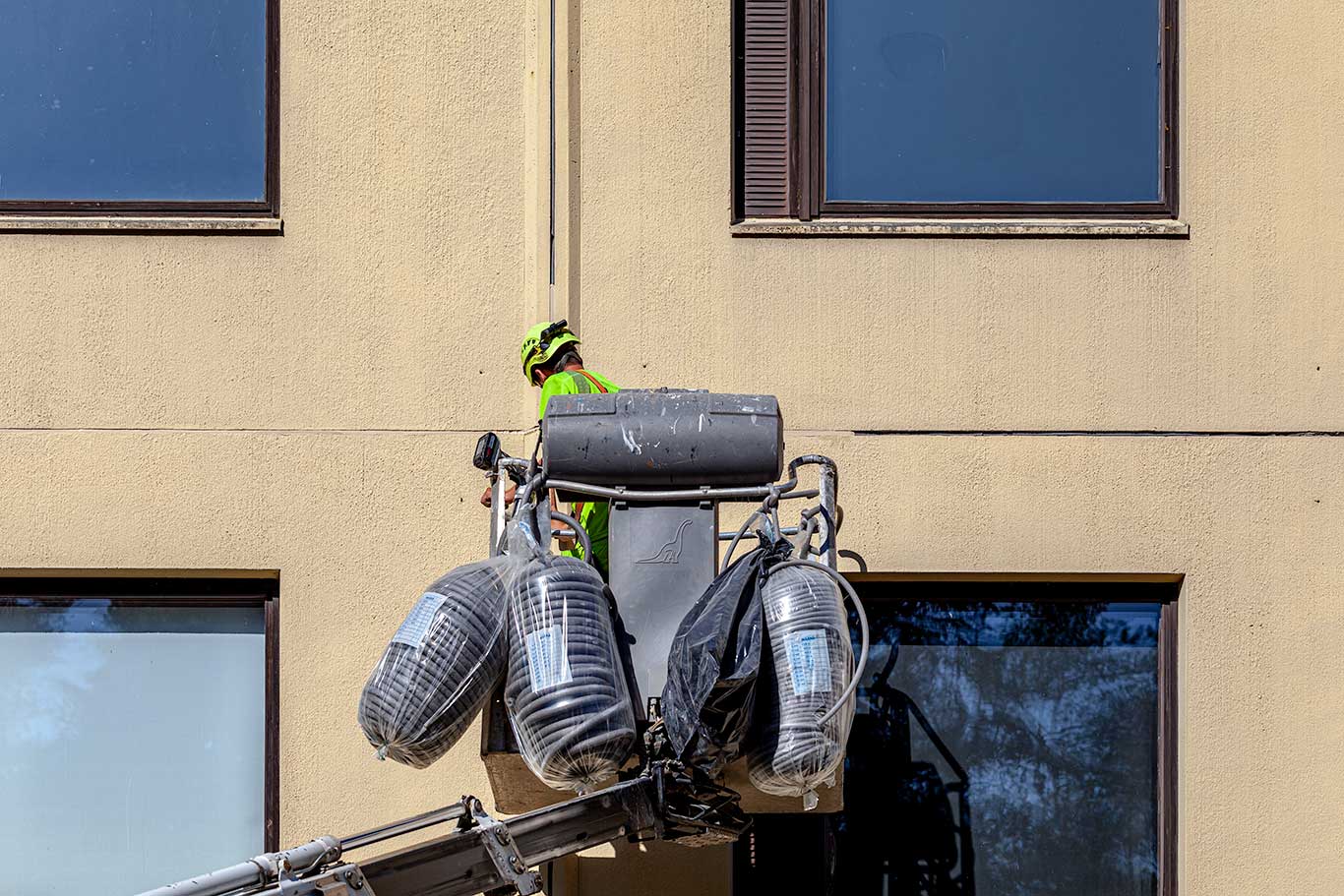 Saumaaja työskentelee nostimella kerrostalon julkisivun äärellä